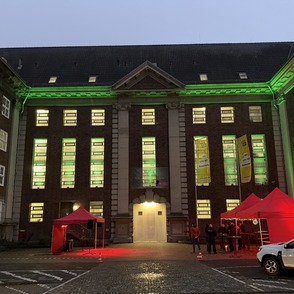 JVA Hamm gr&uuml;n angeleuchtet mit Zelten vor der T&uuml;r