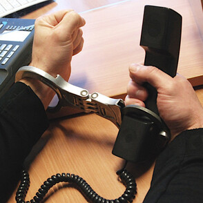 Gefangener mit Handschellen an einen Telefonhörer gefesselt