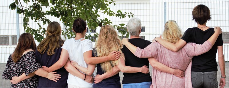 Menschen halten sich im Arm vor einem Hafthaus