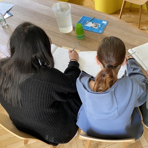Drei Mädchen am Tisch über beschriebene Blätter gebäugt