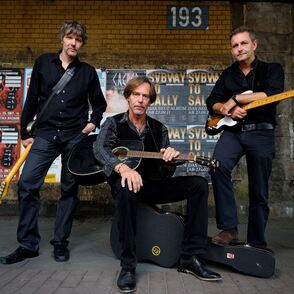 Foto der Band in einer Unterführung vor Plakaten mit Instrumenten