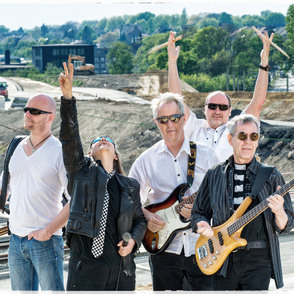 Bandfoto "Empire Rock Building" auf einer Straße vor einer Baustelle, mit Instrumenten