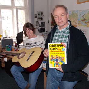 Der stellvertretende Projektleiter KNAST­KULT­UR, Thomas Cieszynski übergibt Gitarren an Frau Schmid-Große vom Päda­go­gisch­en-Dienst der Sozialtherapeutischen Anstalt Gels­en­kirch­en